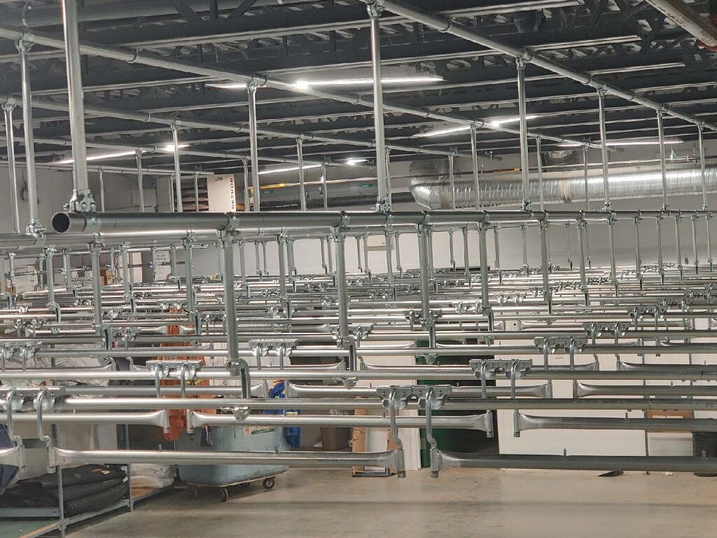 Railex System 200 Trolley Storage area under construction. This trolley storage area is ceiling suspended and comes out from underneath a mezzanine. This area features 20 trolley storage lines. The lines, when complete, will feed directly into the loading dock. Trolleys move into the trucks with Railex telescopic switches that join the rail system in the building to the rail system inside the trucks and vans.