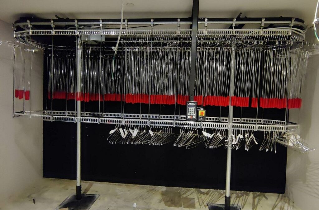 Railex System 742 two tier conveyor that shows our Railex extended hangers. These hang “up” hangers allow the operator to reach garments on the upper tier. This makes the space and the conveyor more useful for higher density. This system is an older system in a performance space for guest coat check.